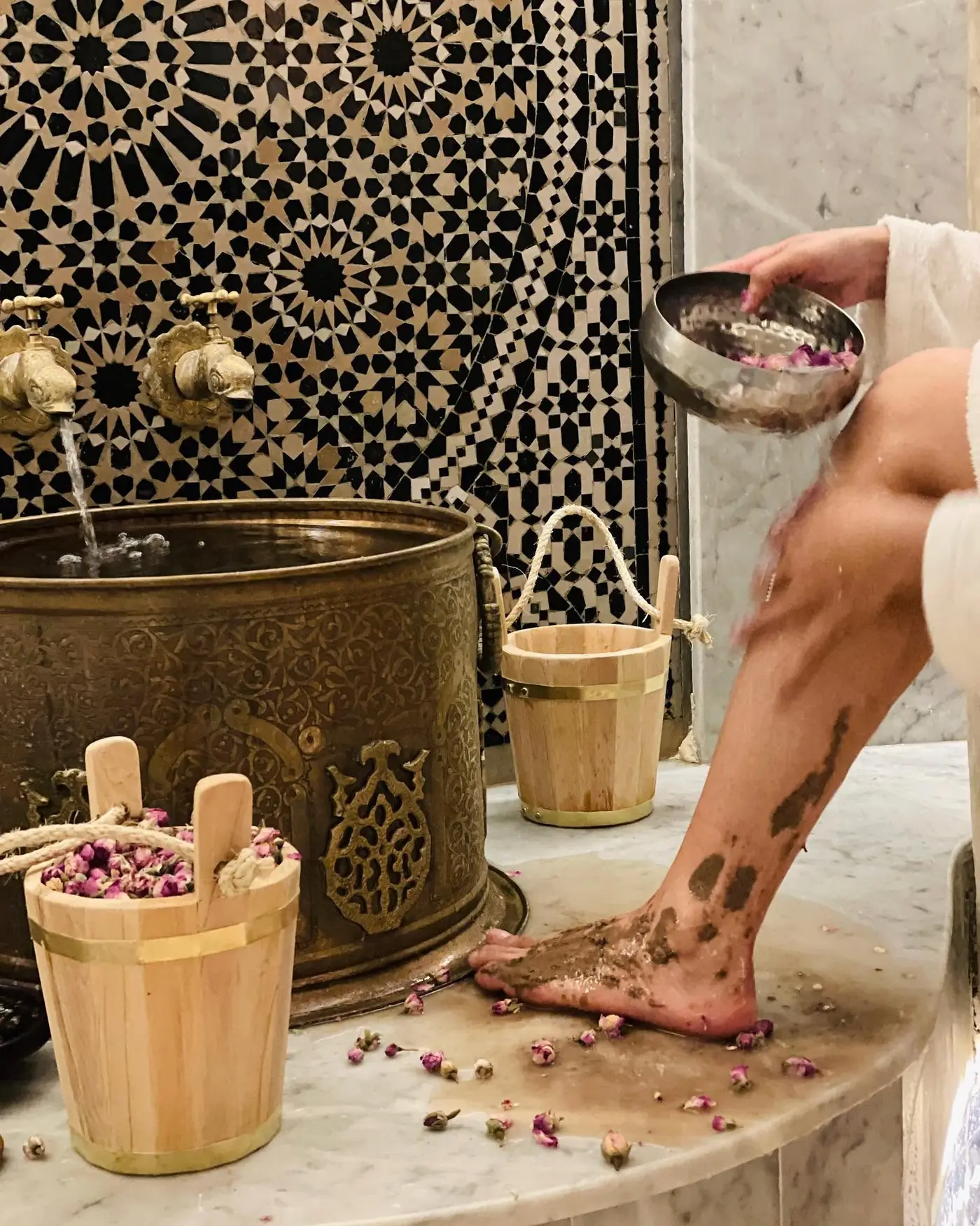 Brass basin, wooden buckets and rose petals during a hammam ritual at Palais Shazam
